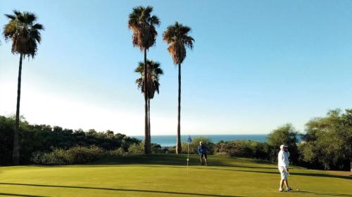 two people playing golf on a golf course with palm trees at Añoreta Suites in Rincón de la Victoria