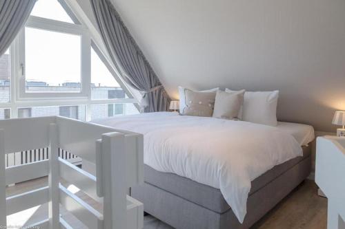 een witte slaapkamer met een groot bed en een groot raam bij Kaept32 _ 15 Mr_ Ocean II in Westerland