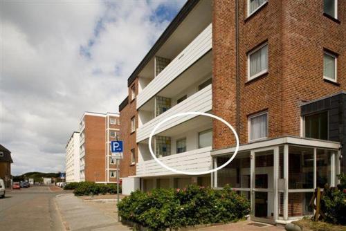 un grande edificio in mattoni con un balcone bianco su una strada di Mar2 6 Strandkoenig 7 a Westerland