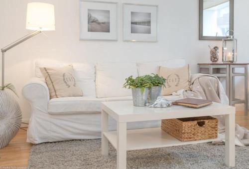ein Wohnzimmer mit einem weißen Sofa und einem Tisch in der Unterkunft Carmen Sylva 11 (Dün12 - 11) in Westerland