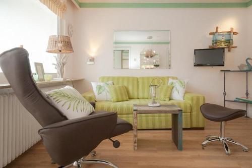 ein Wohnzimmer mit einem gelben Sofa und einem Stuhl in der Unterkunft Duen12_ 9 in Westerland