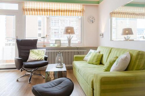 ein Wohnzimmer mit einer grünen Couch und einem Stuhl in der Unterkunft Duen12_ 9 in Westerland