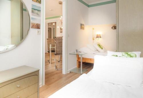 ein weißes Zimmer mit einem Bett und einem Spiegel in der Unterkunft Duen12_ 9 in Westerland