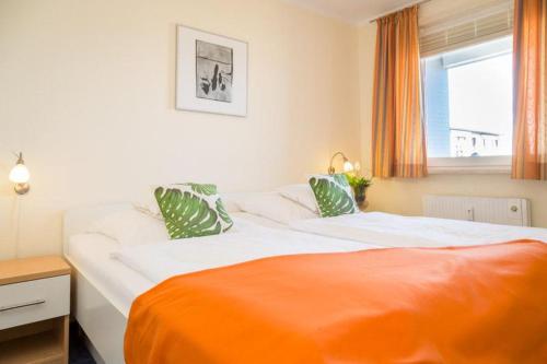 a bedroom with a large bed with an orange blanket at F23 App 25 Kurt S Island in Westerland (Sylt)