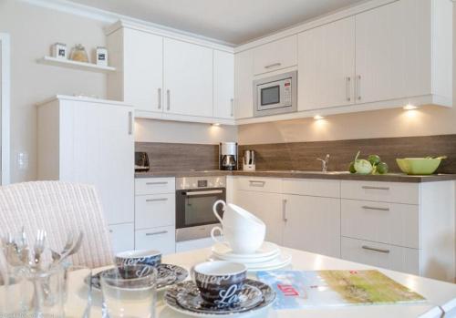 a kitchen with white cabinets and a table with cups at Vik6 9 Viktoria Residenz in Westerland (Sylt)