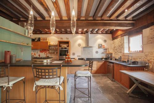 a large kitchen with wooden ceilings and a table and chairs at Locations - Domaine Le Coq Enchanté in Cambremer