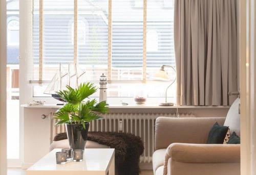 ein Wohnzimmer mit einem Sofa und einem Tisch mit einer Pflanze in der Unterkunft Duen12_27 Sea la Vie in Westerland