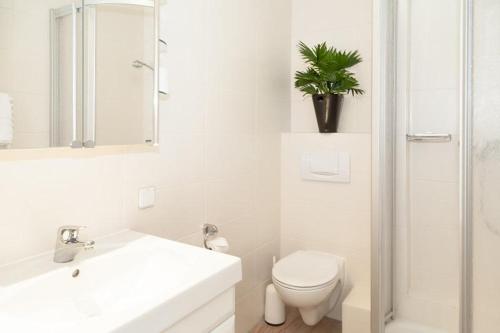 La salle de bains blanche est pourvue de toilettes et d'un lavabo. dans l'établissement Duen12_27 Sea la Vie, à Westerland