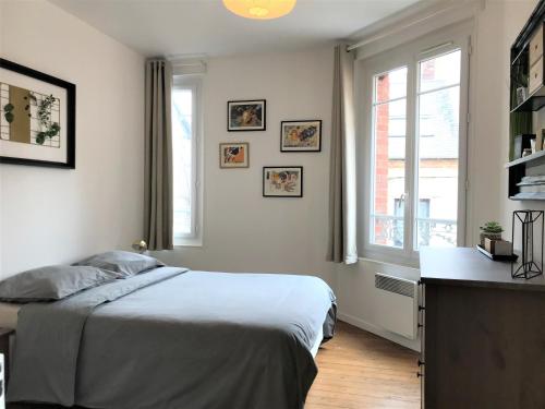 a white bedroom with a bed and a window at Appartements Maisons Bleues in Honfleur