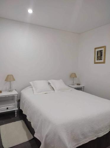 a white bedroom with a large white bed and two tables at Casa Freixedelo in Santa Comba de Rossas