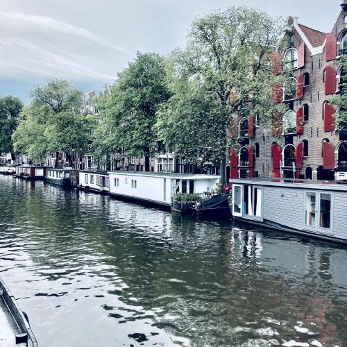 a group of boats on a river in front of buildings at Houseboat Bonnie in Amsterdam