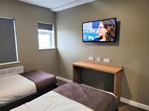 a bedroom with a bed and a tv on the wall at The Oakwood Hotel in Gloucester
