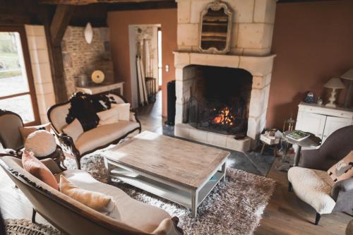 a living room with a fireplace with couches and a table at Locations - Domaine Le Coq Enchanté in Cambremer