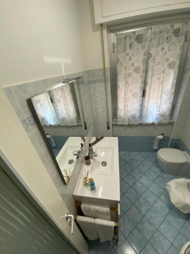 La salle de bains est pourvue d'un lavabo, d'un miroir et de toilettes. dans l'établissement Dodo home beach, à Lavagna