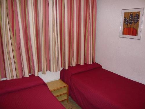 Zimmer mit 2 roten Betten und einem Vorhang in der Unterkunft Aparthotel Condor in Pas de la Casa