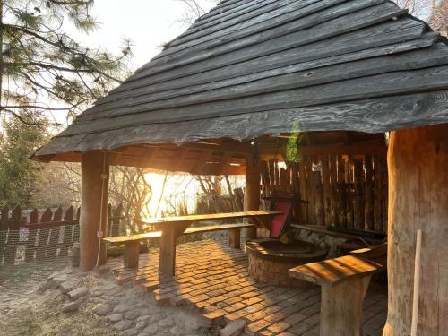 a wooden pavilion with a picnic table and benches at Domek Mazury nad Jeziorem in Langendorf