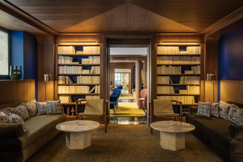 a living room with a couch and chairs and book shelves at Pavillon Faubourg Saint-Germain & Spa in Paris