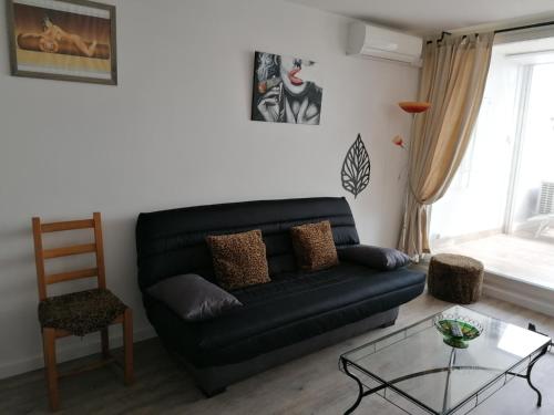 ein Wohnzimmer mit einem schwarzen Sofa und einem Glastisch in der Unterkunft Cap Agde Natu Port Ambonne in Cap d'Agde