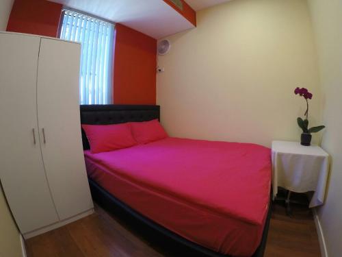 Un dormitorio con una cama con sábanas rosas y una mesa. en lilihostel, en Melbourne