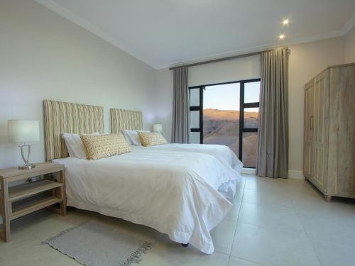 a bedroom with a white bed and a large window at Highland Gate Ferox Creek in Dullstroom