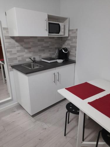 a kitchen with white cabinets and a sink and a table at Your Independent Room with parking in Lecco