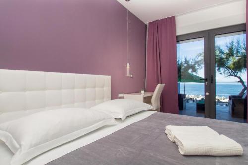 a bedroom with a white bed with a view of the ocean at Luxury rooms Beach Mediteran in Podstrana