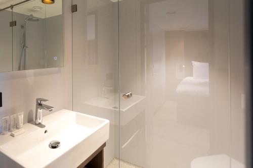 ein weißes Bad mit einem Waschbecken und einer Dusche in der Unterkunft Hotelboot Koningin Emma I Kloeg Collection in Vlissingen