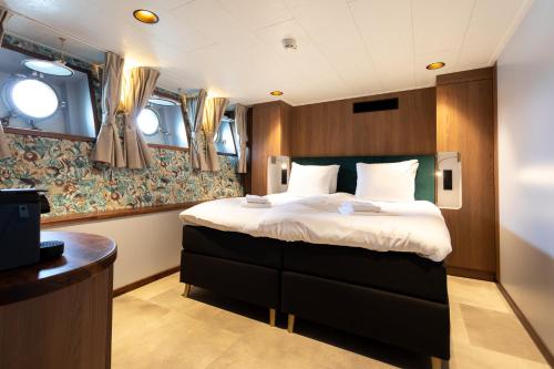 ein Hotelzimmer mit einem Bett und einem Schreibtisch in der Unterkunft Hotelboot Koningin Emma I Kloeg Collection in Vlissingen
