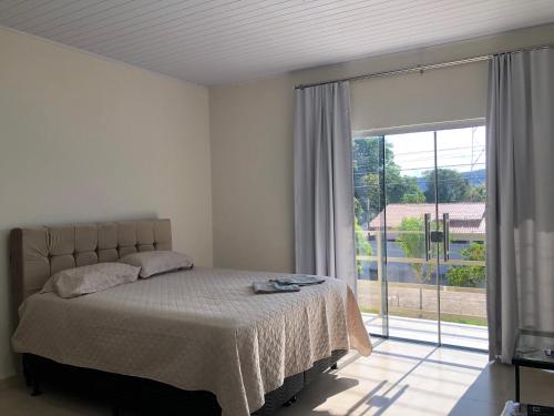 - une chambre avec un lit et une grande fenêtre dans l'établissement Pousada Recanto Lajeado, à Lajeado