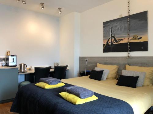 1 dormitorio con 1 cama grande con almohadas amarillas y azules en Bolton Boulevard Beach Rooms, en Vlissingen