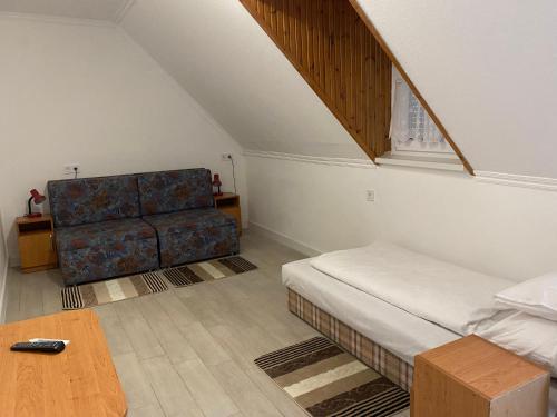 um quarto com uma cama, um sofá e uma mesa em Pipacs Vendégház em Bogács
