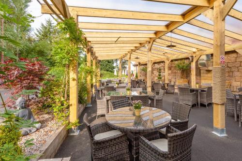 a patio with tables and chairs under a wooden pergola at Anglers Arms in Alnwick