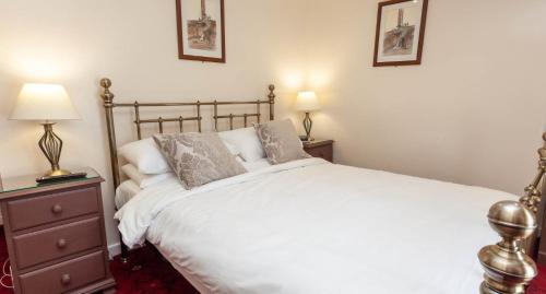 a bedroom with a large white bed and two lamps at Anglers Arms in Alnwick