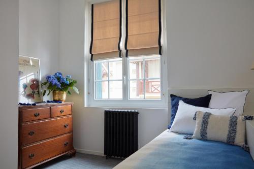 a bedroom with a bed with a dresser and a window at Le Flaubert in Trouville-sur-Mer