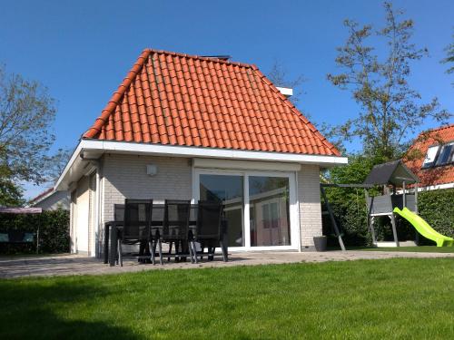 une maison avec une table et des chaises dans une cour dans l'établissement VacationVilla Noordwijk, à Noordwijk
