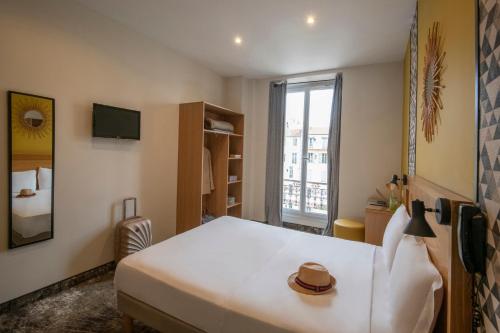 Un dormitorio con una gran cama blanca y una ventana en Hotel d'Ostende, en Niza