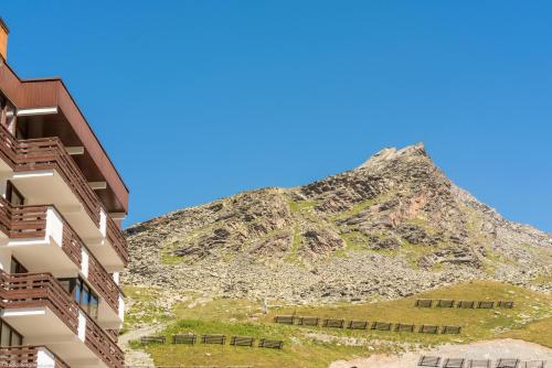 une montagne derrière un bâtiment avec une colline en arrière-plan dans l'établissement Résidence partenaire Le Schuss, à Val Thorens