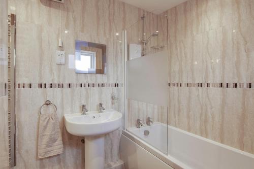 een badkamer met een wastafel en een ligbad bij Rosevean Cottage St Agnes in St. Agnes 