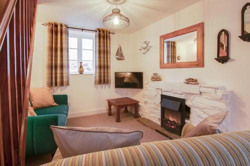 a living room with a fireplace and a green couch at Rosevean Cottage St Agnes in St. Agnes