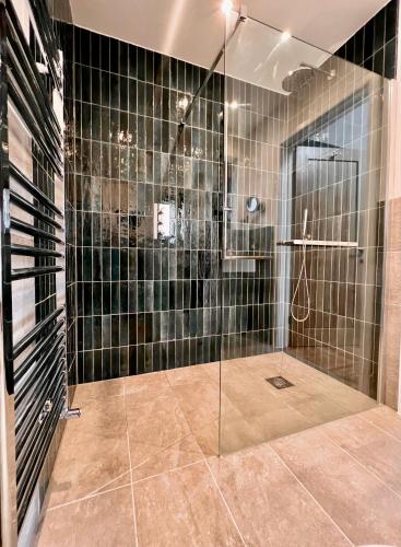 a bathroom with a shower with black tiles at Gwel an Heyl, Padstow in Little Petherick