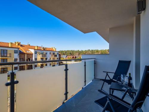 a balcony with two chairs and a view of a city at Apartament Baltic Sunrise in Sztutowo