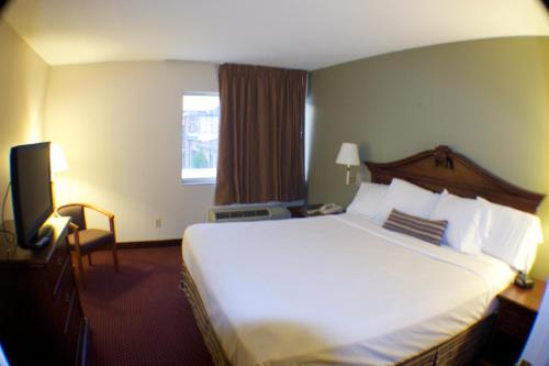 a hotel room with a bed and a television at The Garden Inn in Elkhart