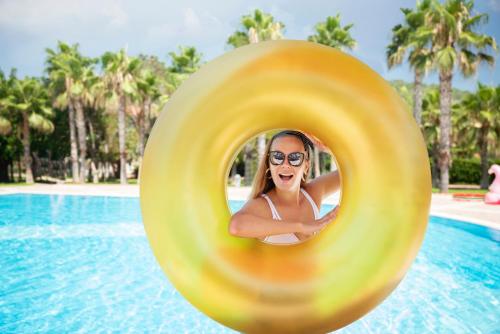 a woman in a swimming pool with a yellow frisbee at Akka Alinda Hotel - Premium Ultra All Inclusive in Kemer