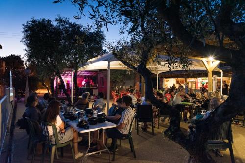eine Gruppe von Menschen, die an Tischen vor einem Restaurant sitzen in der Unterkunft Camping maeva Club Les Rivières in Canet