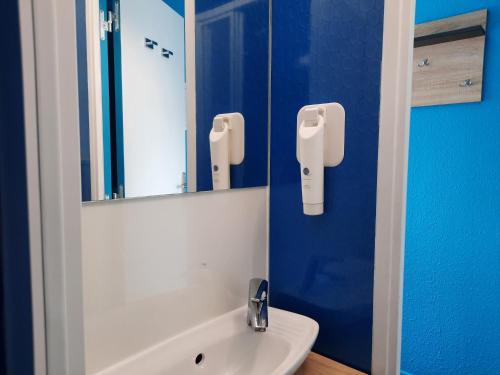 a bathroom with a white sink and a mirror at Kyriad Direct Caen Nord Memorial in Caen