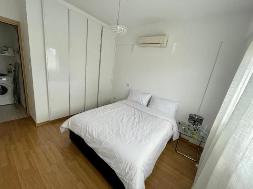 a white bedroom with a bed with white sheets at Amazing 2-bedroom apartment with pool!! in Limassol