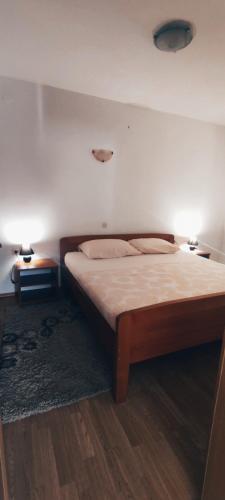 a bedroom with a bed with two tables and two lamps at Apartmani Sršen in Blace