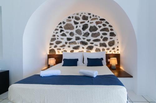 a bedroom with a large bed with a stone wall at DELION VIEW HOTEL in Fira