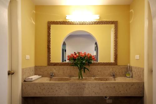 a bathroom with two sinks with a mirror and a vase of flowers at Hotel Sandmelis in Quito
