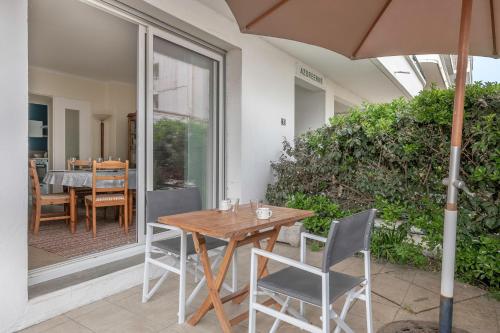 une terrasse avec une table et des chaises en bois ainsi qu'un parasol dans l'établissement 70m de la mer ! Appartement pour 4 à La Baule, à La Baule